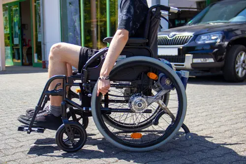 Mann im Rollstuhl vor dem barrierefreien Eingangsbereich von Göhr Rehahilfen.