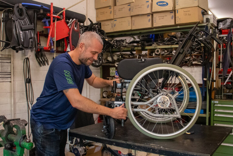 Ein Mitarbeiter arbeitet an individuellen Anpassungen eines Rollstuhls in der Werkstadt